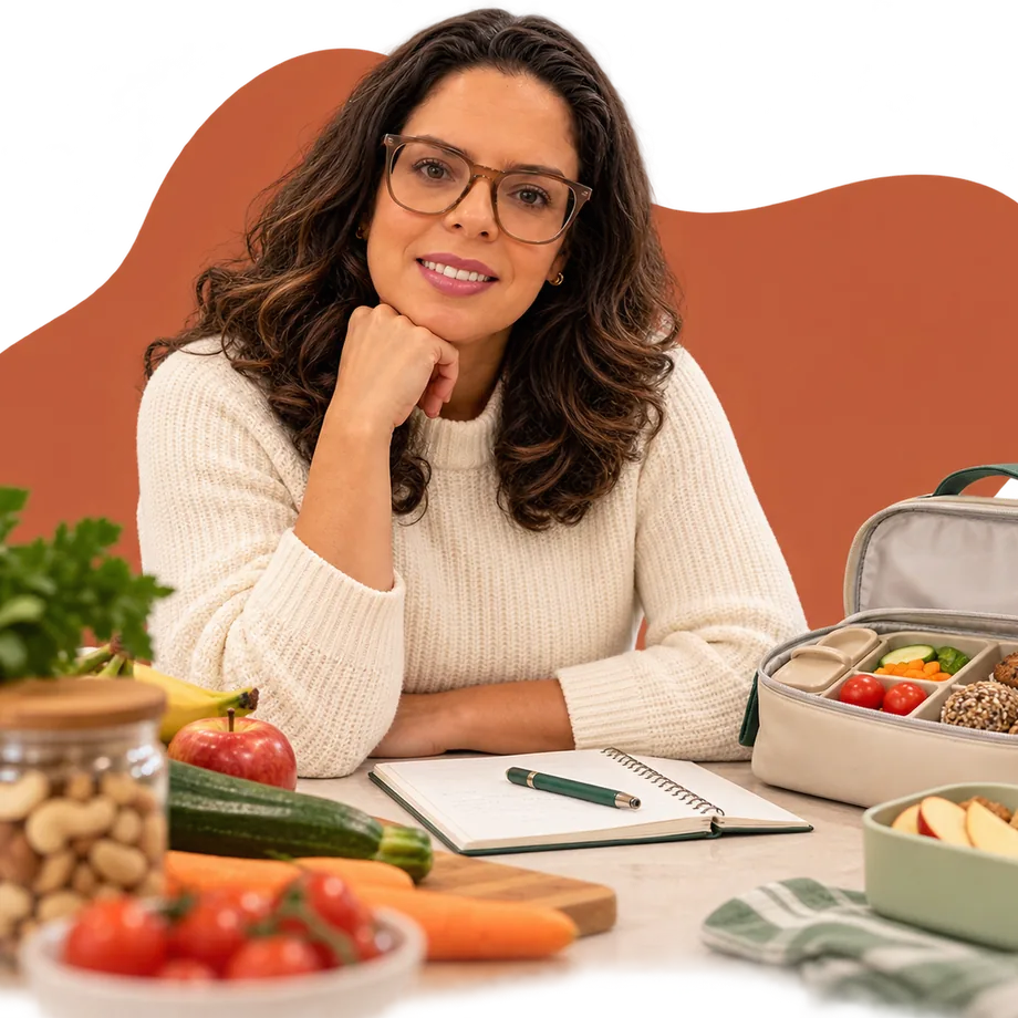Karla Crespo sorrindo à mesa, com legumes, frutas e uma lancheira